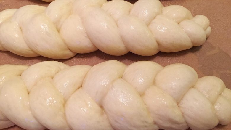 三股辫子面包,均匀地朝面包胚上喷洒蛋黄液