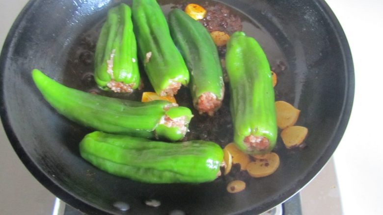 青椒酿肉,煸炒出香味后将酿好的青椒放入里面先干煸一下；