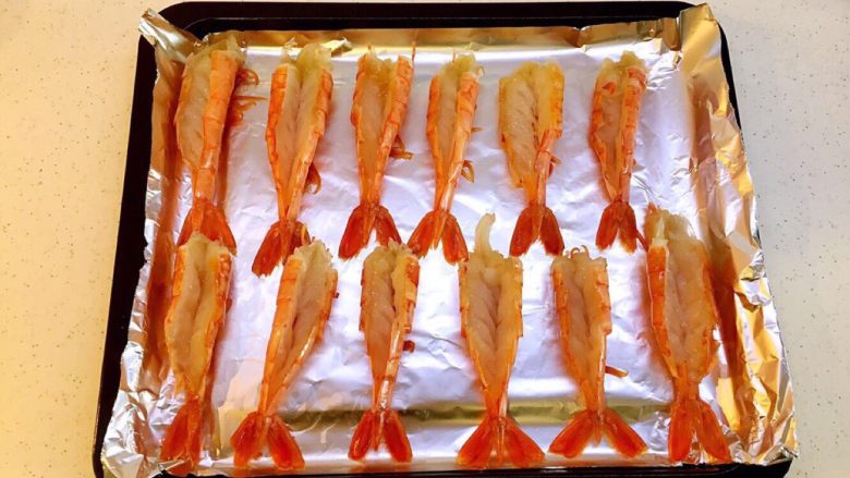 蒜蓉芝士阿根廷红虾#美食拔草大作战#,第二步 摆入烤盘
烤盘中铺好锡纸，使红虾可以很平整的摆放在烤盘中，注意摆放的时候，要把尾巴张开，这样放得更平稳。