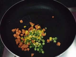 什锦炒饭,锅中倒油，放入玉米粒、青碗豆和火腿肠炒熟后盛起