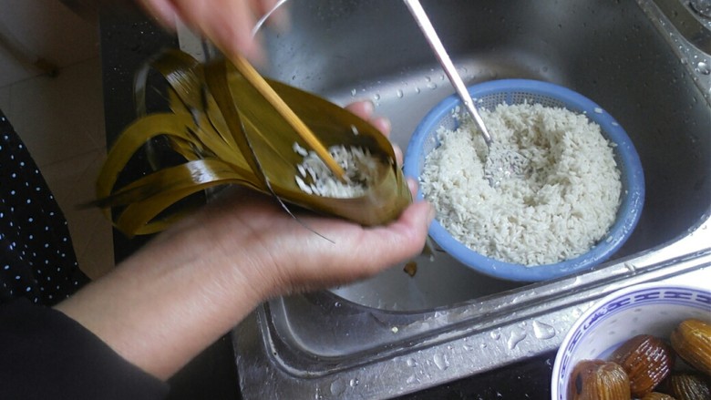 传统红枣粽,用勺子将少许糯米放在漏斗中，用筷子戳实，然后在放一颗红枣进去