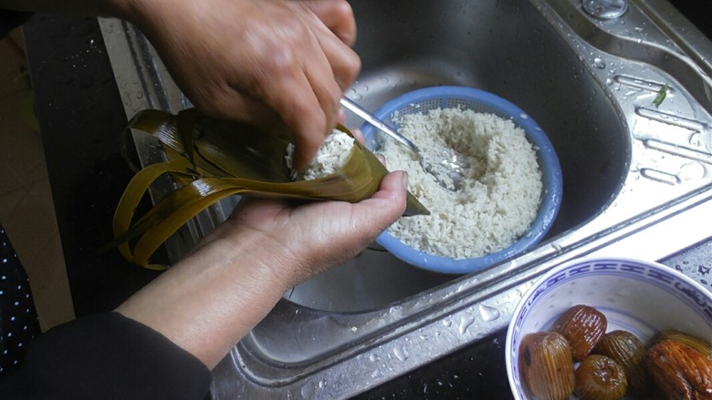传统红枣粽,放入红枣后，在用勺子挖少许糯米，将红枣盖住即可。接着在用手把糯米给推紧实一点