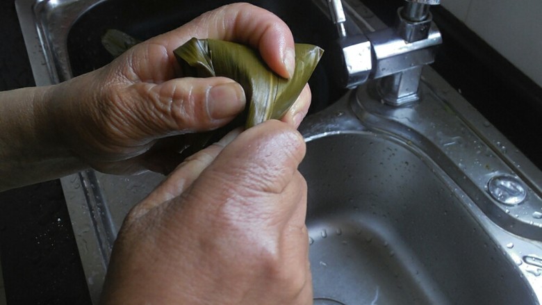 传统红枣粽,然后将上方的粽叶折过来，同样也要拉紧一点，然后将剩余的粽叶小尾巴顺着粽子裹一下就可以了