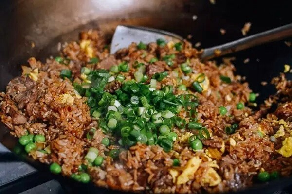 牛肉炒米饭,待米饭炒热后调入适量盐，酱油，最后撒上，青豆，小葱花炒均即可出锅。