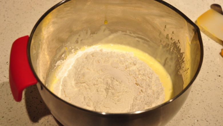 蓝莓爆浆麦芬,将过筛后的粉类混合物全部加入到黄油溶液中。