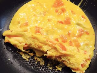 番茄厚烧蛋,将这一层蛋卷起来，放在边边上。在边上倒上适量蛋液。