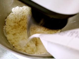 椰蓉花卷面包,分次分量倒入牛奶，把面粉和成面团。