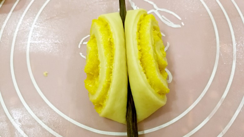 椰蓉花卷面包,取一个小面卷，用筷子在中间轻压一下。