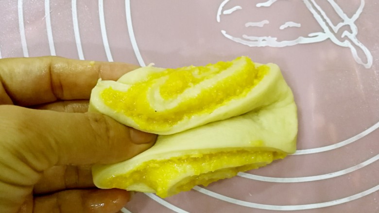 椰蓉花卷面包,双手手指捏着两头。（右手在拍照，因此图中只看到左手的姿势）