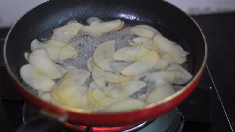 苹果花土司盒,苹果片切好后，我们开始把白糖倒进锅里，加入水，开火把白糖融化一下。糖水沸腾后把苹果片放进去，烫一下，苹果片软化立刻关火，煮久了苹果的颜色会变