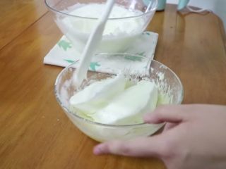 天使蛋糕卷,分两次混合蛋黄糊与蛋白霜，先加1/3蛋白霜到蛋黄糊中翻拌均匀