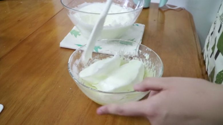 天使蛋糕卷,分两次混合蛋黄糊与蛋白霜，先加1/3蛋白霜到蛋黄糊中翻拌均匀