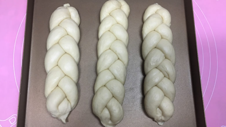 淡奶油辫子面包,将其它面团也同样方法编好，移入烤盘，放在烤箱中，用烤箱自带的发酵功能进行二次发酵，时间为35分钟左右.