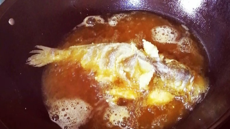 茄汁大黄鱼,锅里放油，油温7成熟时，一手提起鱼尾巴，另一手用勺子舀起锅内油淋到鱼身上，直到鱼肉微微变白，把鱼放入锅内，表面金黄酥脆，捞出把鱼放入盘中