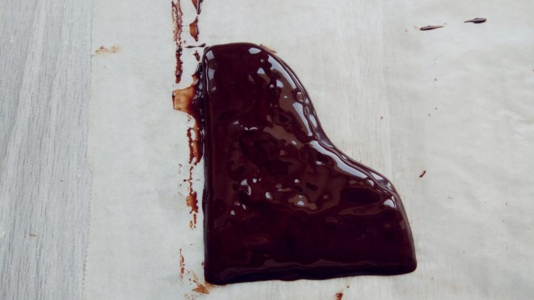 可可钢琴蛋糕,另外用微波炉融化少许黑巧克力，装入剪口裱花袋，在油纸上画出钢琴盖的形状，入冰箱冷藏至凝固。同样用白巧克力涂成长条薄片，冷藏至凝固