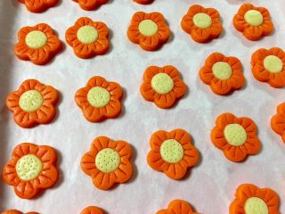 黄金芝士太阳花饼干,开始预热烤箱145度，用牙签在花瓣上压出花瓣痕迹，在花心的部分扎上小洞，花花就绣好了。
