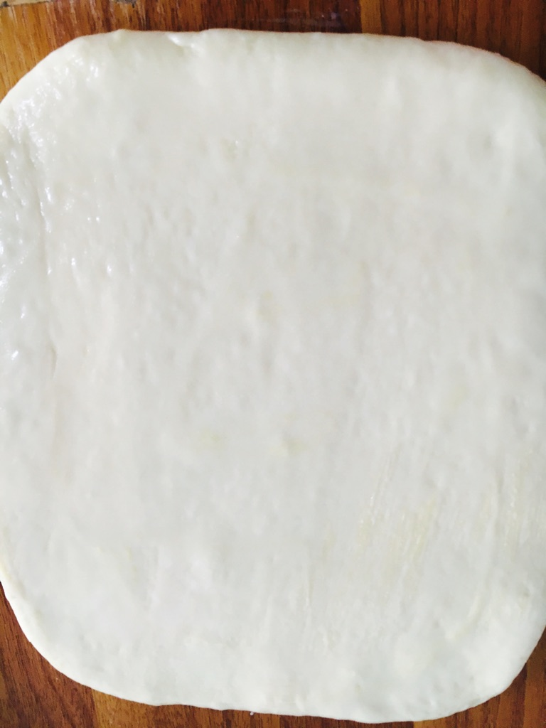 日式香浓练乳面包,从底部捞出，排气擀平，涂上练乳。切成4等份