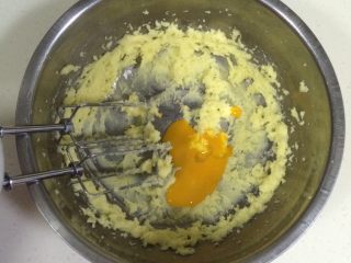 葡萄干奶酥,分三次加入蛋黄液（剩下少许蛋黄液刷表面），并用打蛋器搅打均匀。