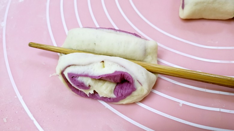 紫薯花卷,取一个剂子，用筷子横在中间向下压一下。