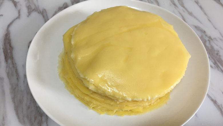 芒果千层蛋糕,将摊好的饼皮放在一个盘子里,摊熟的饼皮这样叠着放也不会粘在一起.
