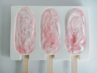 草莓奶油冰棒,也可以一勺奶油一勺草莓汁倒入模具，再用筷子简单搅拌几下，不要搅拌均匀形成大理石花纹
