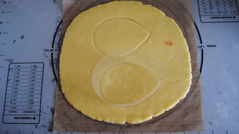 花环糖霜饼干,取出用擀面杖擀成0.5cm高度的面片，用慕斯圈模具印出椭圆形