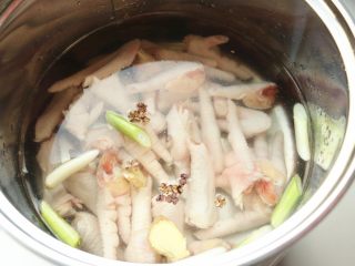 红油鸡爪,汤锅加水，加葱段姜片和八角一个，放入鸡爪。