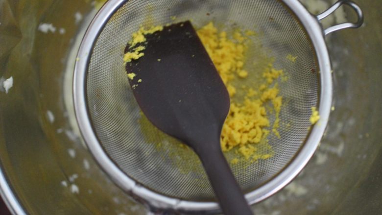 巧克力豆玛格丽特饼干,然后将煮熟的蛋黄过筛到黄油盆子里。用刮刀压按的方式过筛很容易过筛下去的。