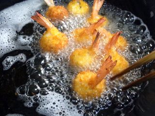 黄金虾球,在锅内倒入食用油，烧至六七成热，把虾球入油锅内炸制，虾球刚下过别急的翻动。待虾球一定炸制固定了再翻动其他面继续炸制。
