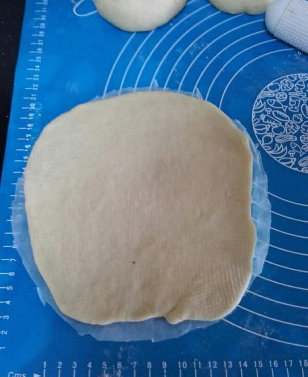 网纹红豆面包,剪一块和八寸圆模差不多的油纸，将擀卷好的面团放到油纸上面。