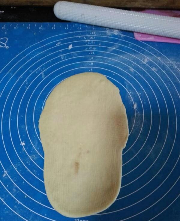 网纹红豆面包,将另外一个大面团擀卷成椭圆形。