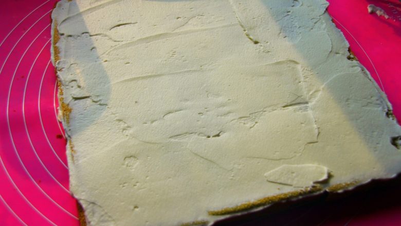 抹茶漩涡蛋糕,19．	把打好的奶油抹在蛋糕片上，奶油的厚度最好是要均匀。