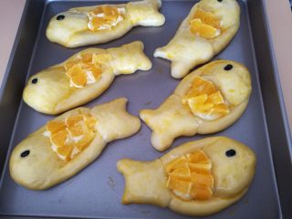 水果鱼面包,13.发酵好的小鱼面团拿出来，刷上鸡蛋液，再放入奶酪，表面放上切碎的橙子。
