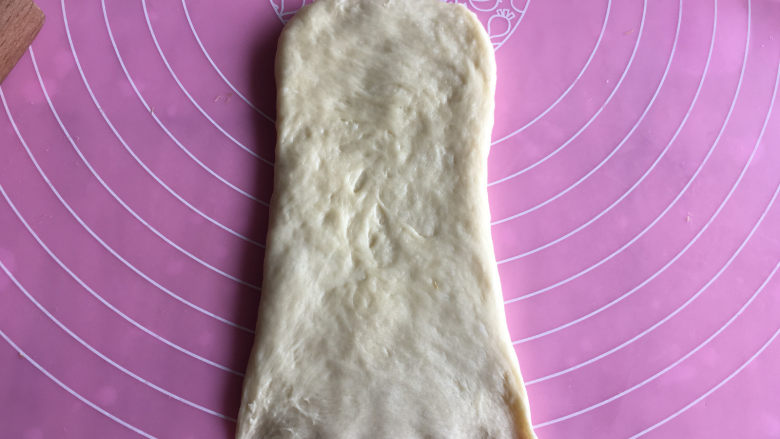 香酥肉松面包,醒面结束后，取一块面团，擀成长方形后翻面，底部按薄。