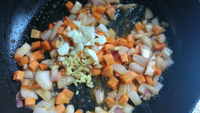 剩米饭华丽大变身——虾仁焗饭,接着放入红萝卜丁，翻炒两下，放入蒜片姜末翻炒均匀。