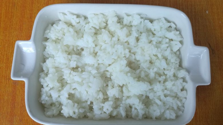 剩米饭华丽大变身——虾仁焗饭,米饭放在烤箱专用的烤盘，铺满。