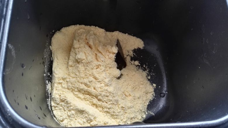 芝麻玉米面白糖饼,玉米面倒容器中（本来想蒸玉米面窝头，临时改变主意做饼，感觉量多馒头机和不下又倒出用手揉的）。