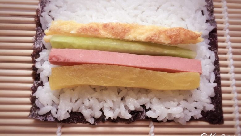 寿司🍣版的欢乐颂五美,寿司席上铺一张海苔，平铺米饭，勺子按压实，放入腌制萝卜，火腿肠，黄瓜，鸡蛋，一样一条，放在米饭上