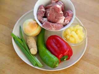 咕咾肉,1.备好材料：猪里脊肉（或梅花肉）300克、菠萝100克、青椒1个、红甜椒1个、洋葱1个、葱1根、姜3克