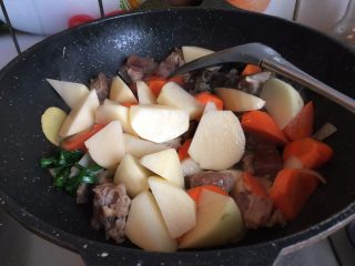 熊猫咖喱牛肉饭,接着加入胡萝卜块、土豆块翻炒片刻
