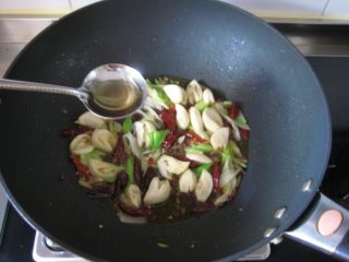 川香麻辣烤鱼：麻辣过瘾的豪华烤鱼,放入葱姜蒜，大火炒出香味，烹入料酒。
