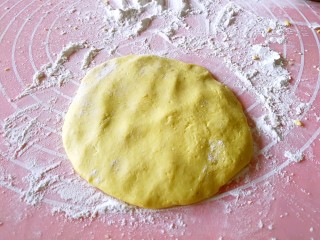 粗豆沙南瓜饼,从大面团上揪下一小块面团，揉圆，放在铺洒了糯米粉的案板上，压扁。