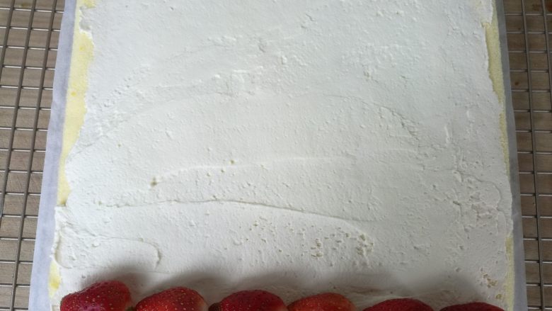 草莓蛋糕卷,用抹刀把打发好的奶油平铺在蛋糕体上，（留一点奶油用在蛋糕表面），放上洗净晾干的草莓。