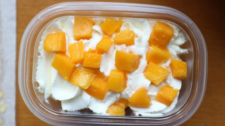 芒果盒子蛋糕,然后在挤一层奶油，在撒上一层芒果粒即可。做好后用盖子盖好，送进冰箱冷藏一会在吃口感更佳！