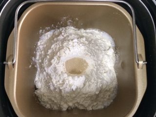 超软椰蓉面包,除黄油以外的面包材料都放入面包机内（先液体后粉类的顺序），在面粉中间挖个洞，把酵母粉倒进去，启动和面程序。