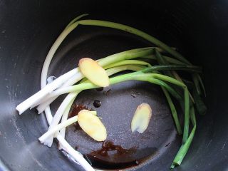 凉拌猪耳朵,将葱和生姜铺在电饭煲锅底