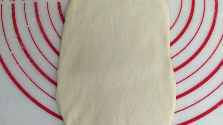 热狗面包,取一个松弛好的面团，擀成椭圆形的面片。