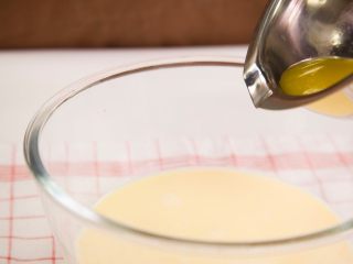 香蕉可丽饼,取25g黄油，隔水加热软化，慢慢倒入蛋奶糊中搅拌均匀。