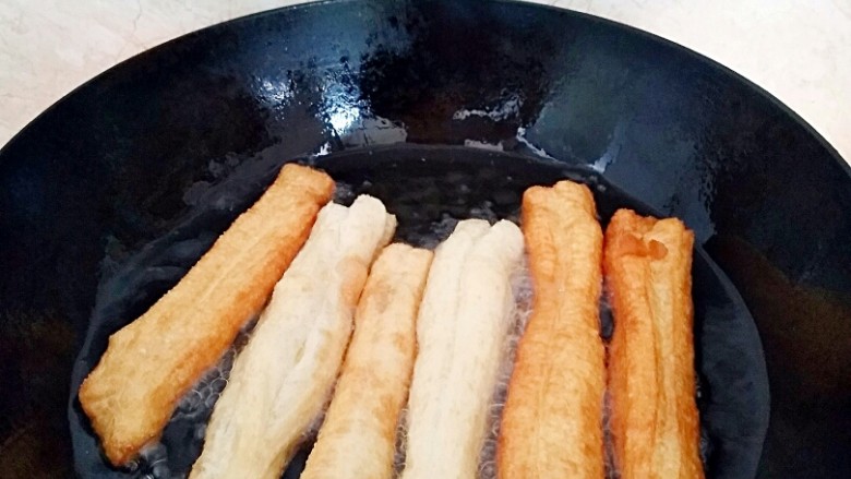 早餐油条,放入油条胚用筷子快速翻面，还需要多次翻面中小火炸。