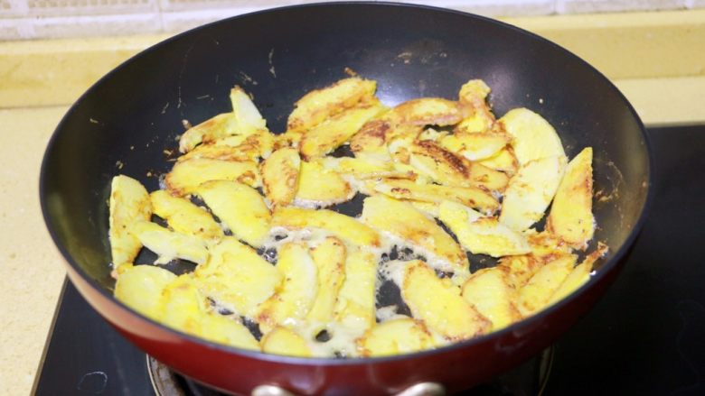 蛋黄煎杏鲍菇,待一面煎至金黄微卷时，将杏鲍菇翻面，继续煎至两面金黄